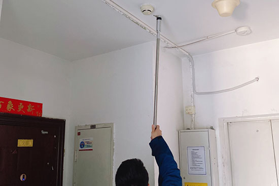 消電檢人員使用檢測桿對辦公室煙感探測器進(jìn)行測試